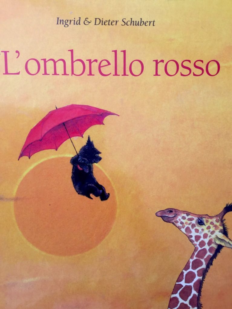 Immagine di un cane che vola appeso ad un ombrello rosso e giraffa che lo guarda